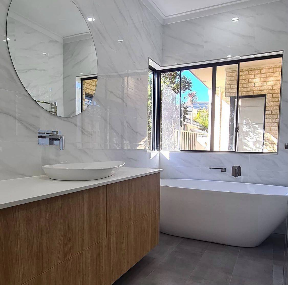 Completed bathroom renovation by INNA GROUP — frameless shower and stone tiling.