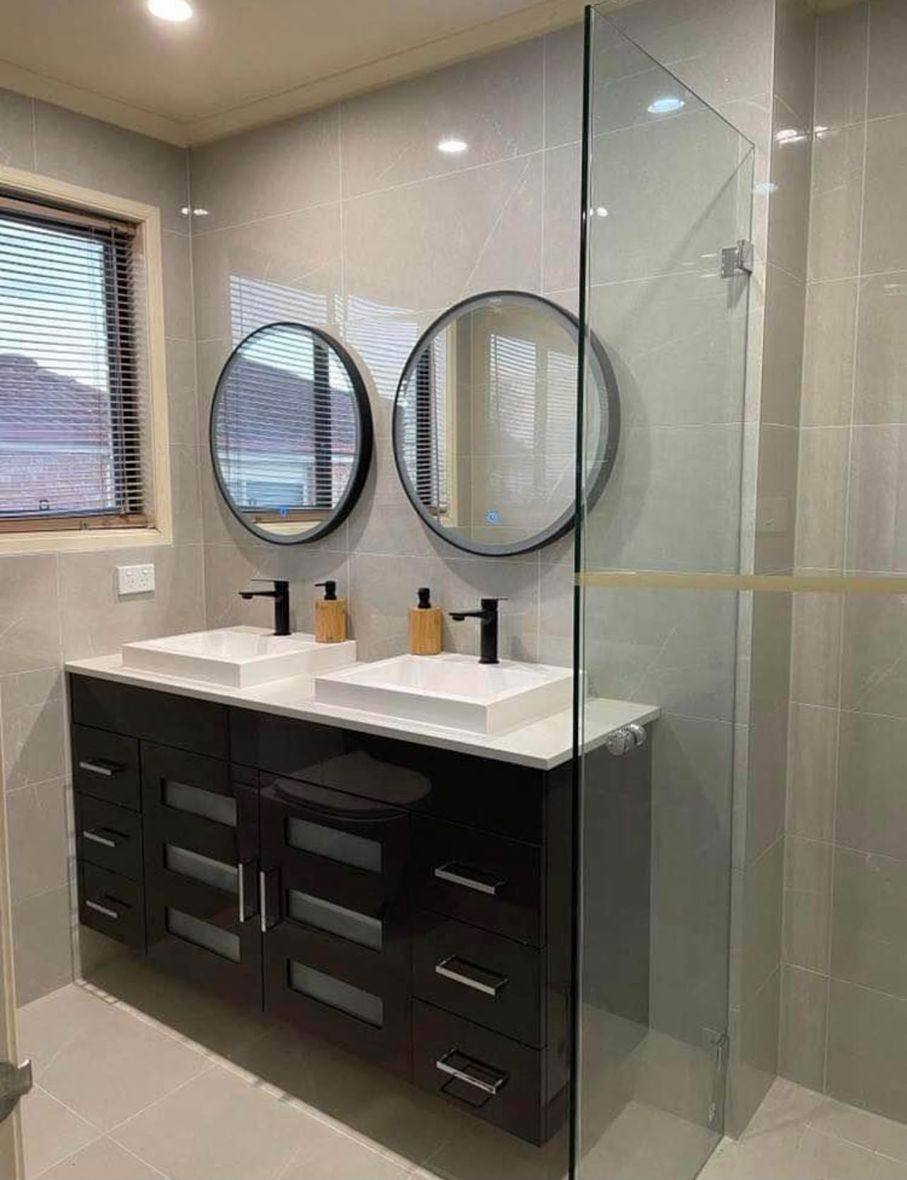 Completed bathroom renovation by INNA GROUP — frameless shower and stone tiling.