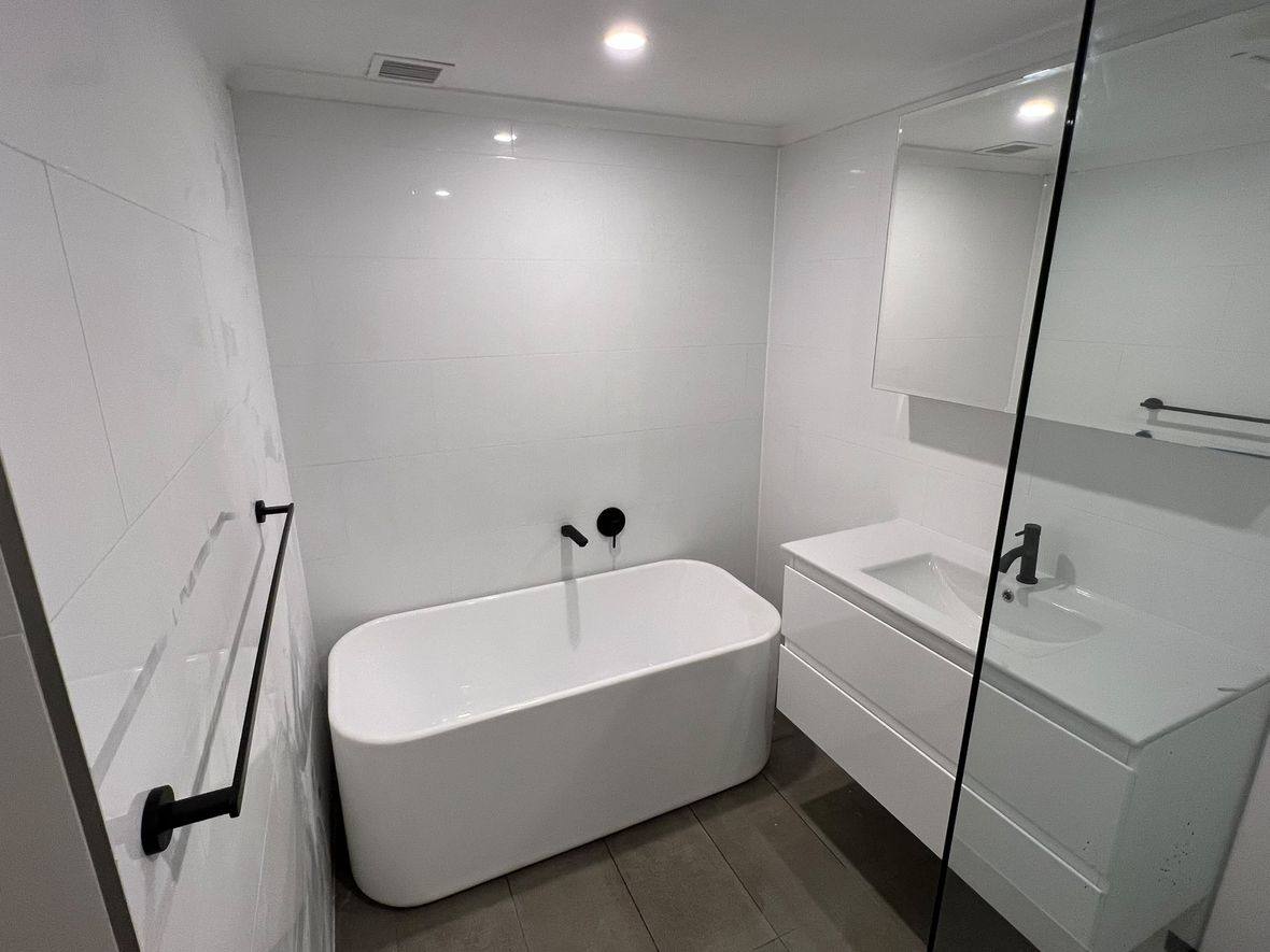 Completed bathroom renovation by INNA GROUP — frameless shower and stone tiling.