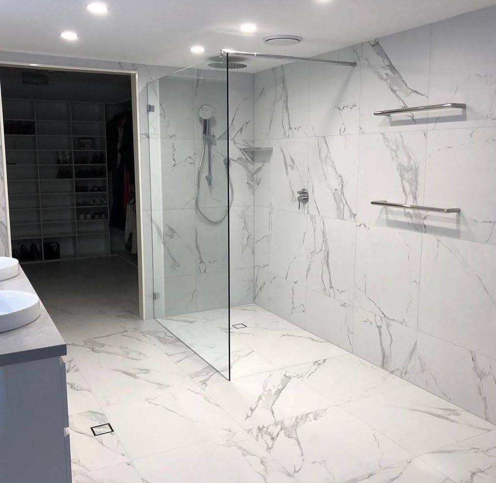 Completed bathroom renovation by INNA GROUP — frameless shower and stone tiling.
